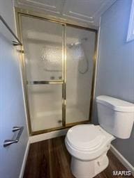 bathroom featuring toilet, a stall shower, baseboards, and wood finished floors