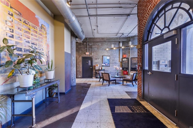 entryway with baseboards, brick wall, a high ceiling, and tile patterned floors