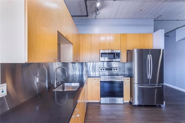 kitchen featuring a sink, appliances with stainless steel finishes, backsplash, dark wood-style floors, and dark countertops