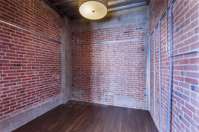 spare room with dark wood-style floors and brick wall