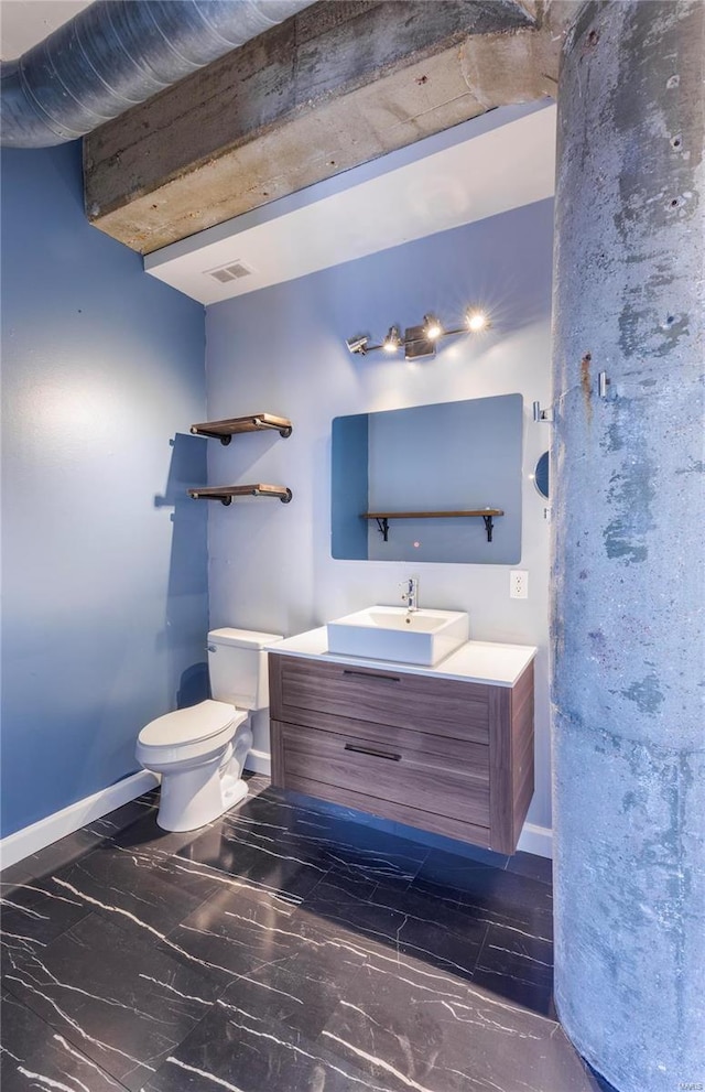 half bath featuring toilet, vanity, visible vents, and baseboards