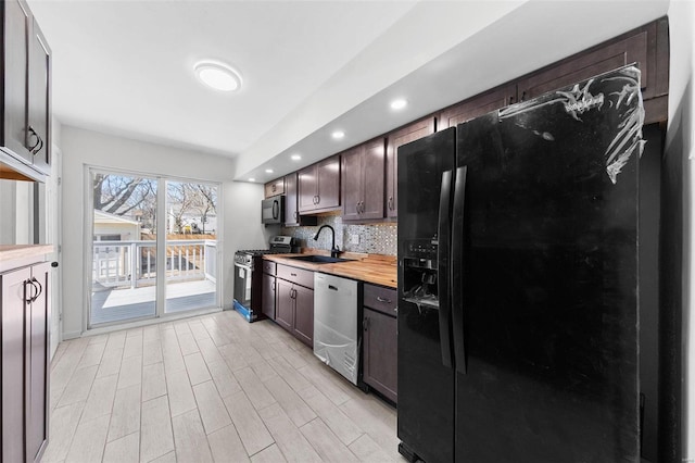 kitchen with tasteful backsplash, dark brown cabinetry, light wood-style floors, black appliances, and a sink
