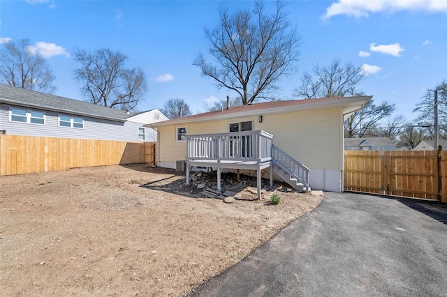 rear view of house with central air condition unit, a deck, and fence