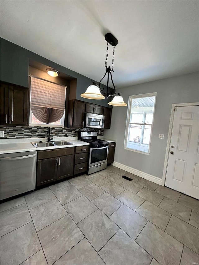 kitchen with appliances with stainless steel finishes, decorative backsplash, a sink, and light countertops