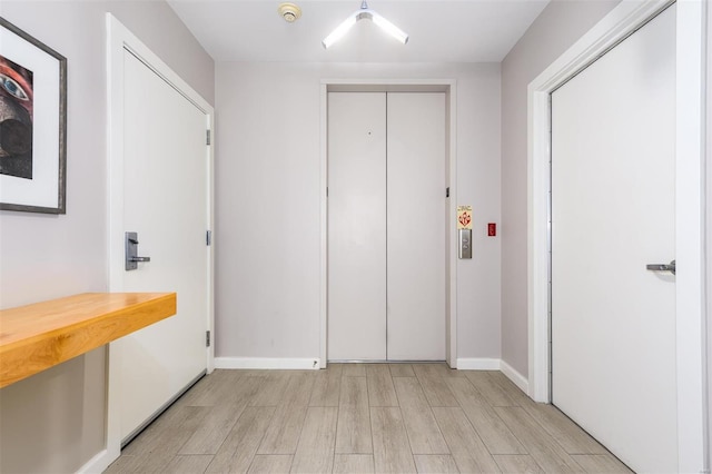 corridor featuring light wood-style floors and baseboards