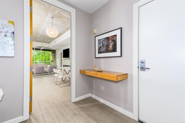 corridor featuring light wood-type flooring and baseboards