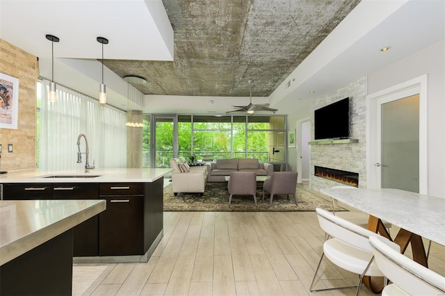 kitchen with a fireplace, a sink, light countertops, hanging light fixtures, and light wood-type flooring