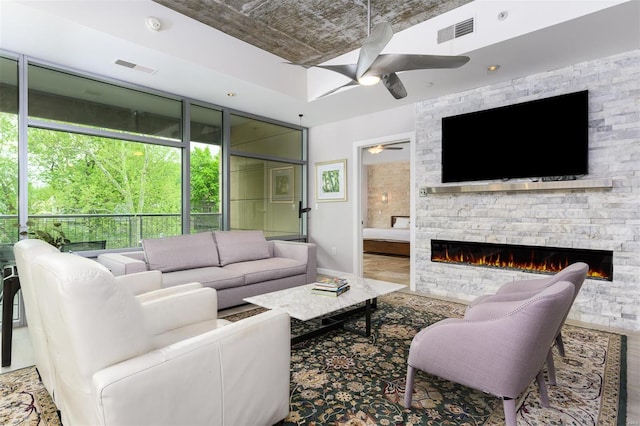 living room featuring a ceiling fan, visible vents, and a fireplace