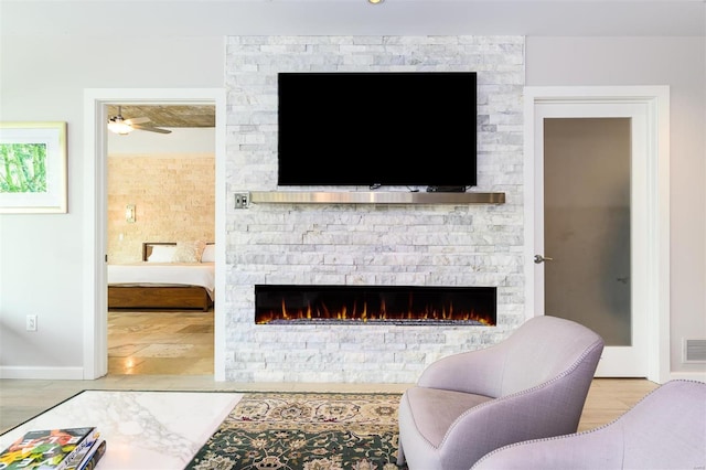 living room featuring visible vents, a fireplace, baseboards, and wood finished floors