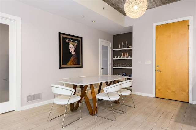 dining space with light wood-style flooring, visible vents, and baseboards