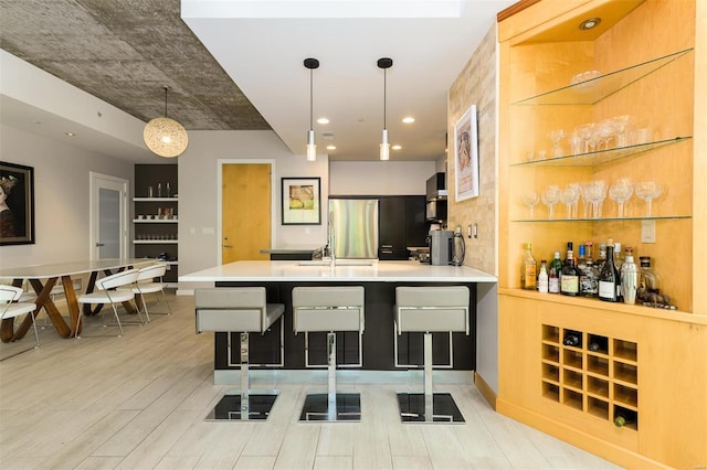 kitchen featuring light countertops, hanging light fixtures, light wood-style floors, freestanding refrigerator, and a peninsula