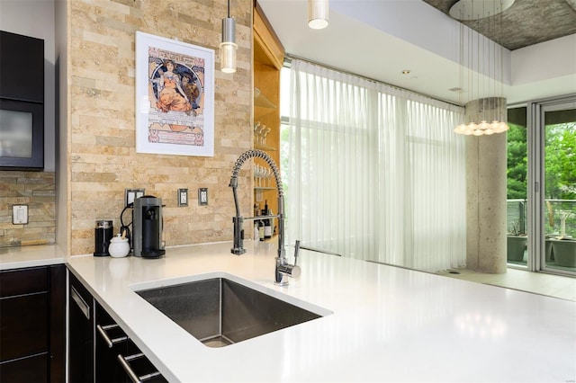 kitchen with light countertops, a sink, decorative light fixtures, and decorative backsplash