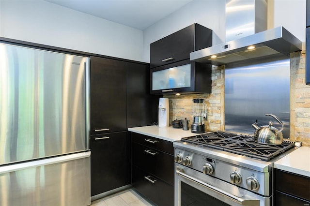 kitchen featuring appliances with stainless steel finishes, decorative backsplash, dark cabinets, and exhaust hood