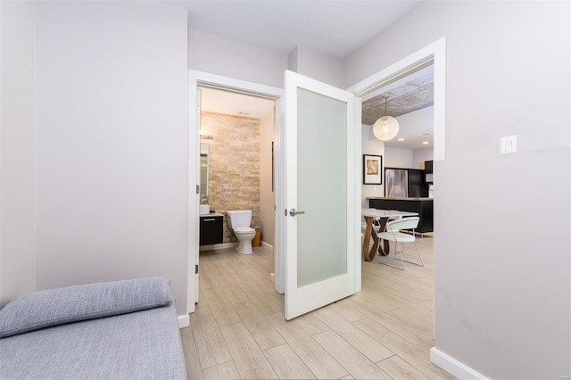 hallway featuring light wood-style floors and baseboards