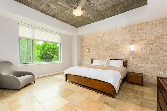 bedroom featuring baseboards, a raised ceiling, and a ceiling fan