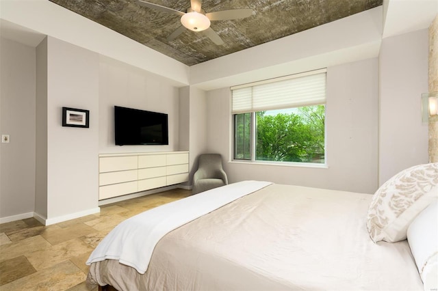 bedroom featuring stone finish floor, a ceiling fan, and baseboards