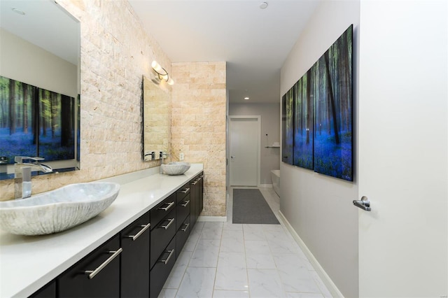 full bathroom with marble finish floor, double vanity, a sink, and baseboards