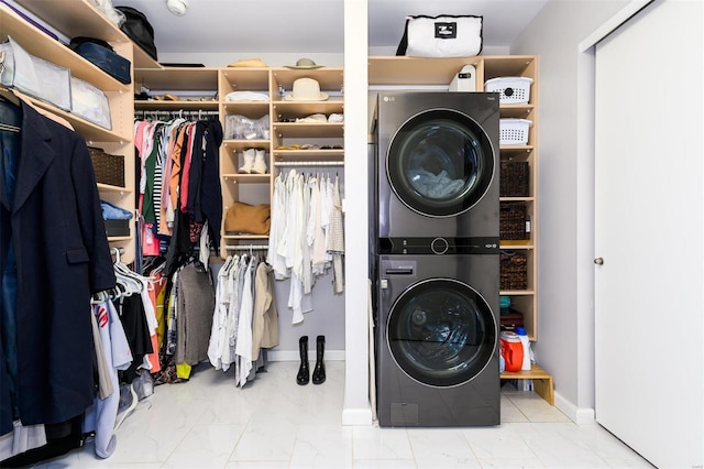 laundry room with stacked washer and dryer, baseboards, laundry area, and marble finish floor