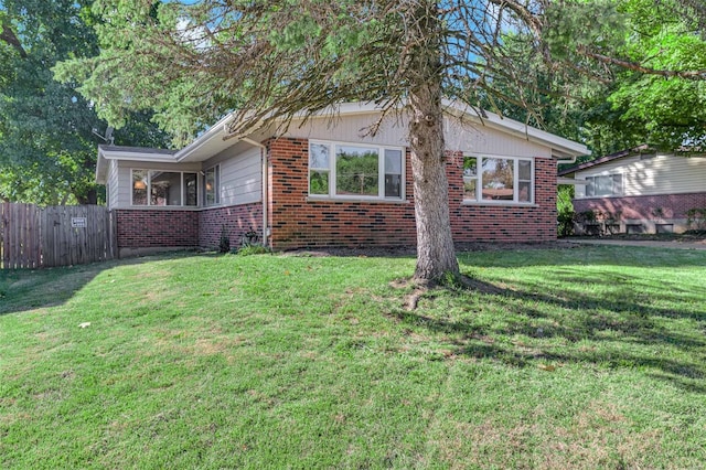 view of property exterior with a yard, fence, and brick siding