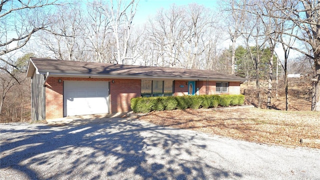 single story home featuring a garage, brick siding, and driveway