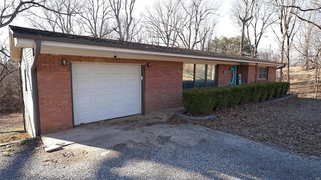 view of front of house with a garage, brick siding, and driveway