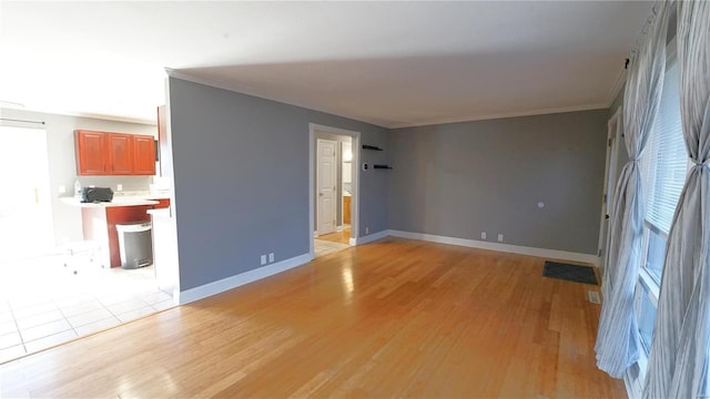 unfurnished living room featuring crown molding, light wood-style flooring, and baseboards