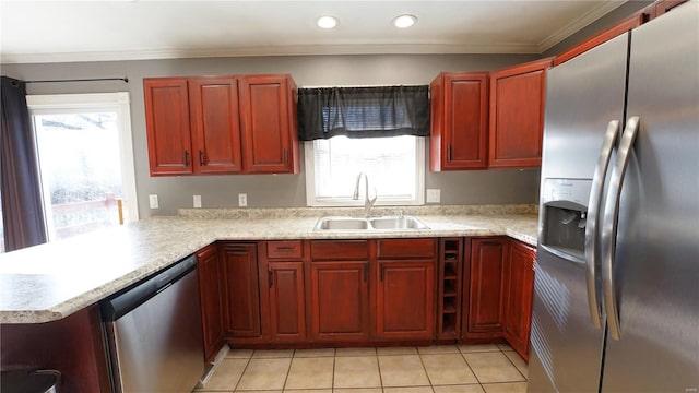 kitchen featuring reddish brown cabinets, light countertops, appliances with stainless steel finishes, and a sink