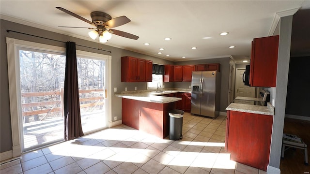 kitchen with a peninsula, light countertops, stainless steel refrigerator with ice dispenser, a wealth of natural light, and reddish brown cabinets