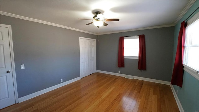 unfurnished bedroom with wood-type flooring, multiple windows, and baseboards