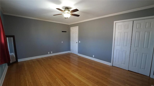 unfurnished bedroom featuring baseboards, wood finished floors, a ceiling fan, and crown molding