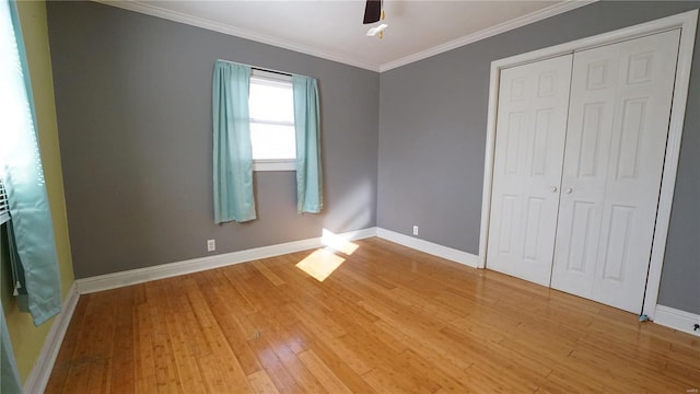 unfurnished bedroom with light wood-type flooring, baseboards, ornamental molding, and a closet