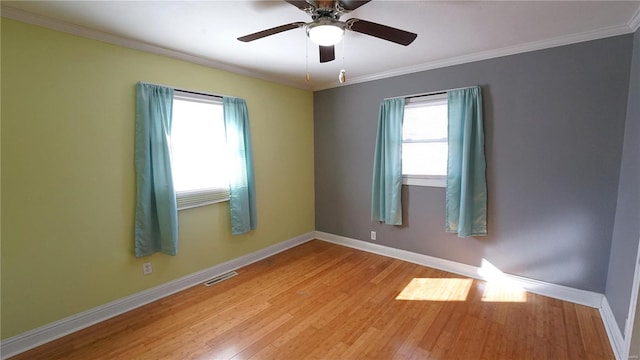 spare room with baseboards, crown molding, visible vents, and wood finished floors