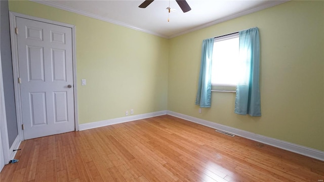 spare room featuring light wood finished floors, baseboards, visible vents, ceiling fan, and crown molding