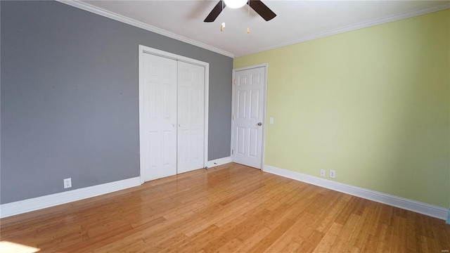 unfurnished bedroom with a ceiling fan, baseboards, a closet, light wood finished floors, and crown molding