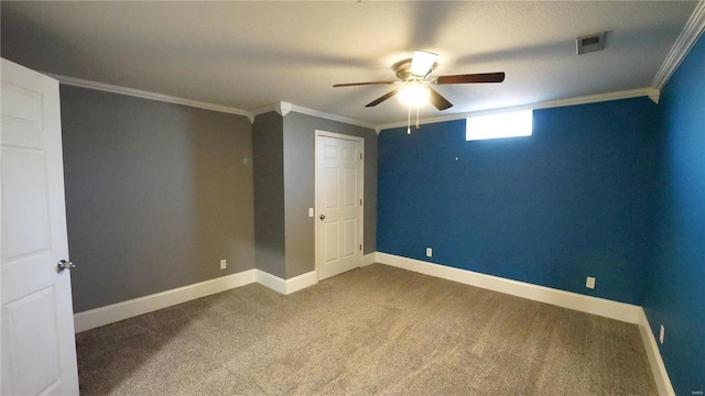 carpeted empty room with baseboards, visible vents, ornamental molding, and a ceiling fan