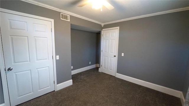 unfurnished bedroom with baseboards, visible vents, dark carpet, and ornamental molding