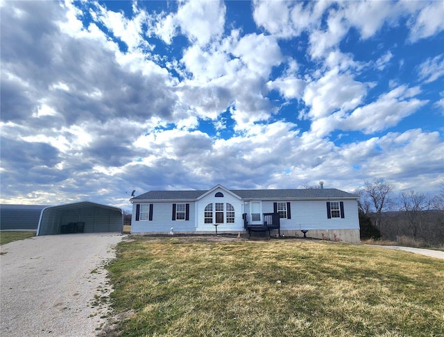 view of front of property with a detached carport, gravel driveway, and a front lawn