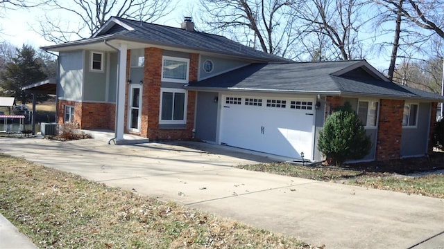 view of front of home with central AC unit, concrete driveway, a chimney, an attached garage, and brick siding