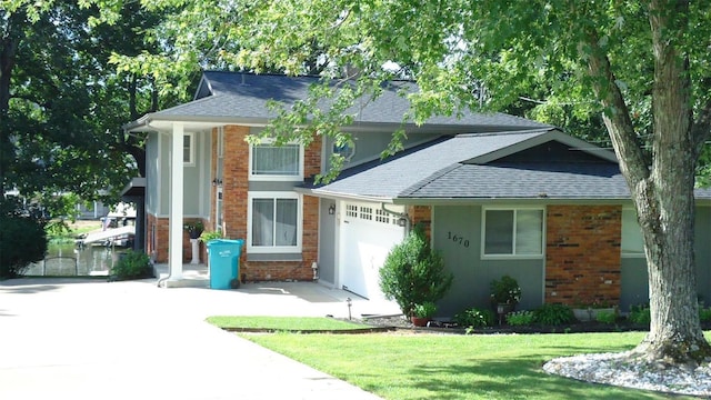 view of front facade featuring a garage, concrete driveway, roof with shingles, a front lawn, and brick siding