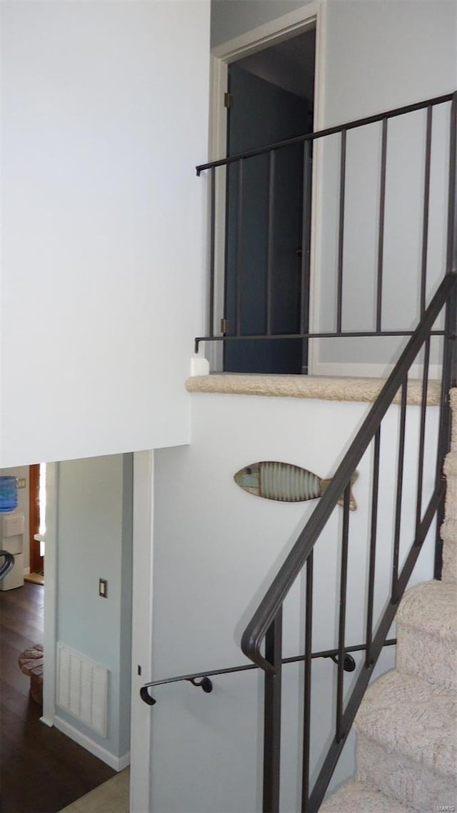 staircase with visible vents and wood finished floors