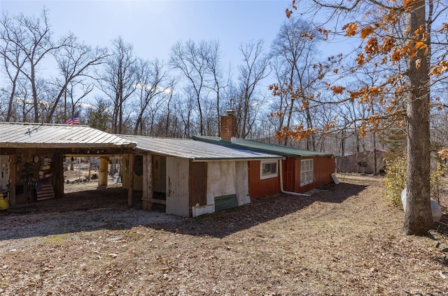 view of side of home featuring a chimney, metal roof, and a carport