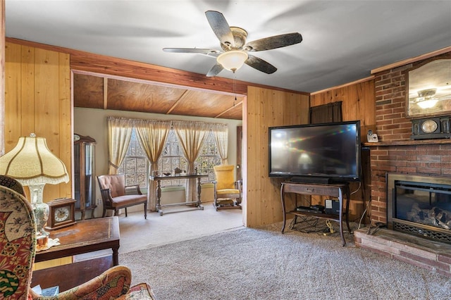 carpeted living area with wood walls, ceiling fan, and a brick fireplace