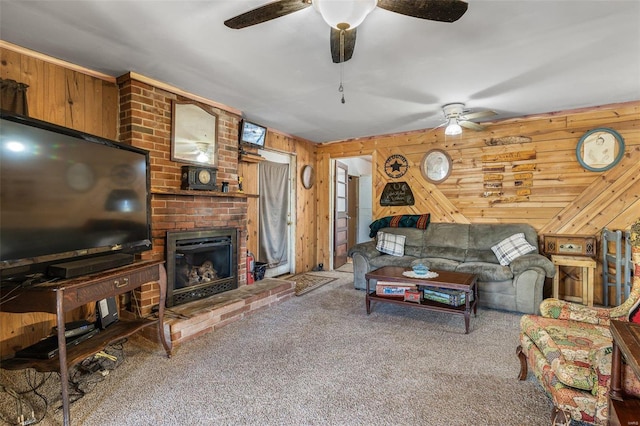 living room with ceiling fan, wood walls, carpet, and a brick fireplace