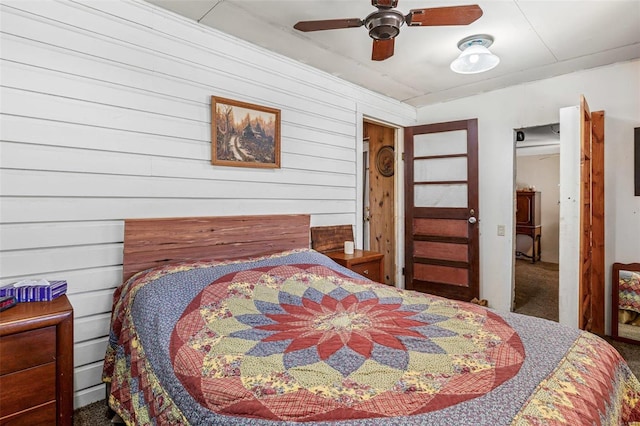 bedroom featuring a ceiling fan, carpet, and wood walls