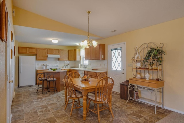 dining area featuring stone finish floor, visible vents, vaulted ceiling, and baseboards