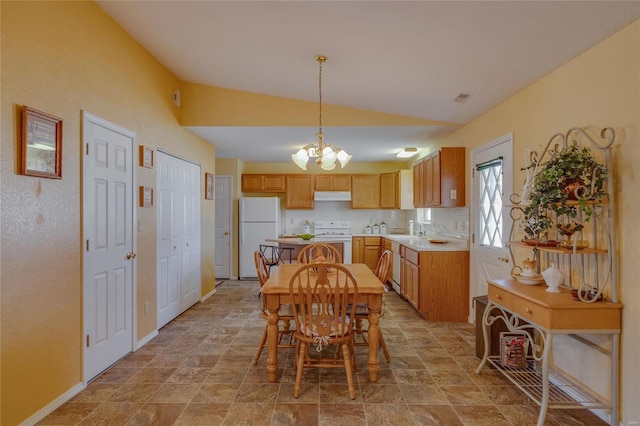 kitchen featuring white appliances, lofted ceiling, light countertops, under cabinet range hood, and a sink