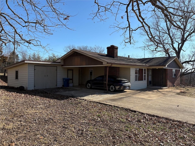 exterior space with a carport, concrete driveway, brick siding, and a chimney