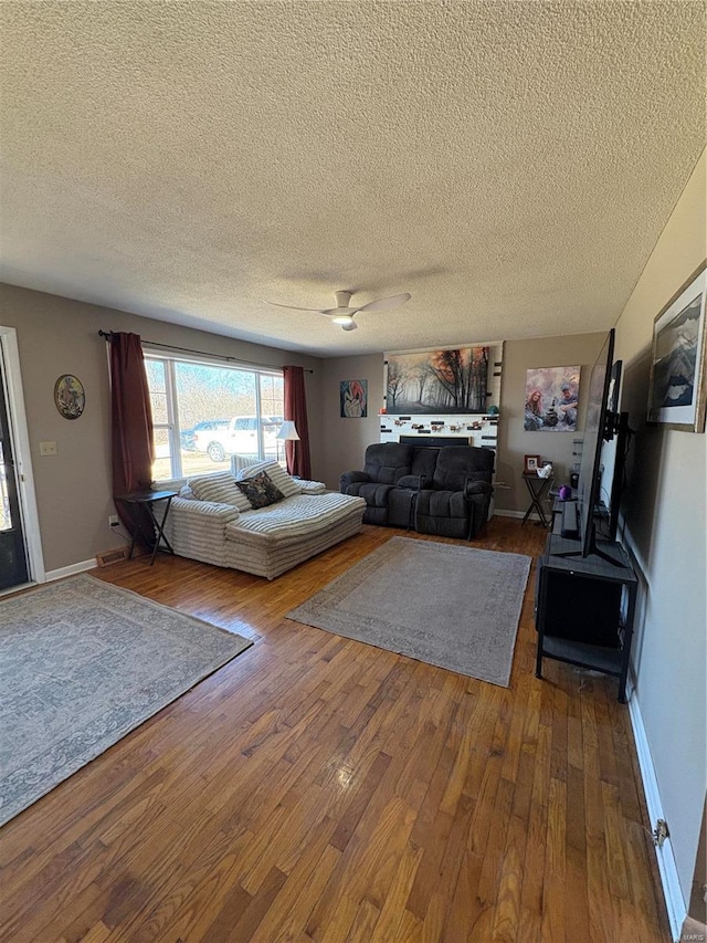 living room with a textured ceiling, hardwood / wood-style flooring, and baseboards