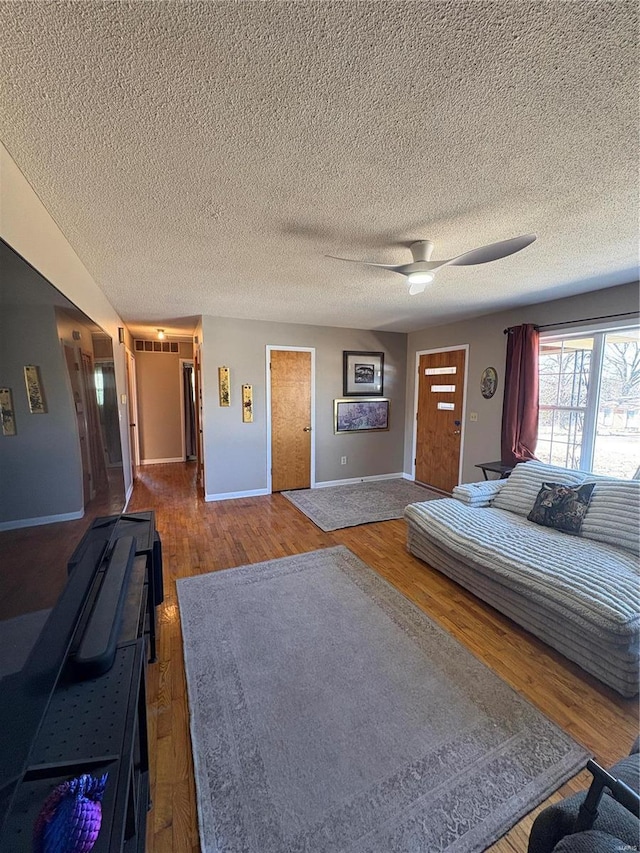 unfurnished bedroom with a ceiling fan, a textured ceiling, baseboards, and wood finished floors