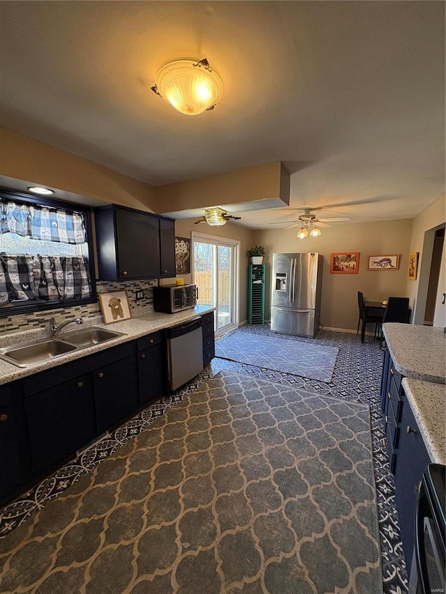 kitchen with stainless steel appliances, light countertops, a ceiling fan, a sink, and dark cabinetry